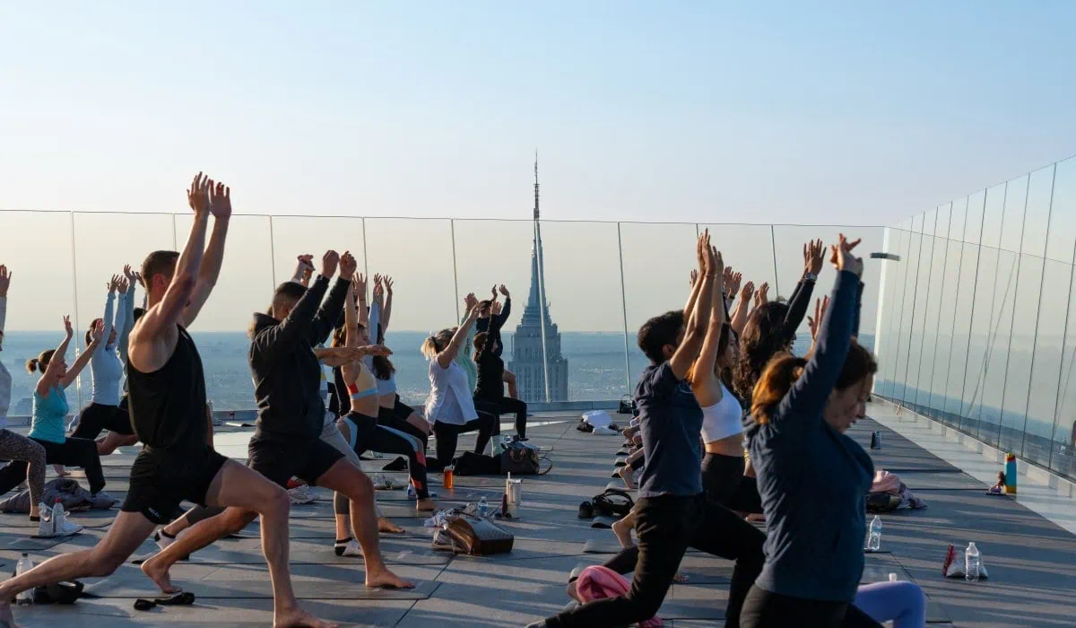 People practicing yoga on Edge NYC outdoor sky deck with skyline view.