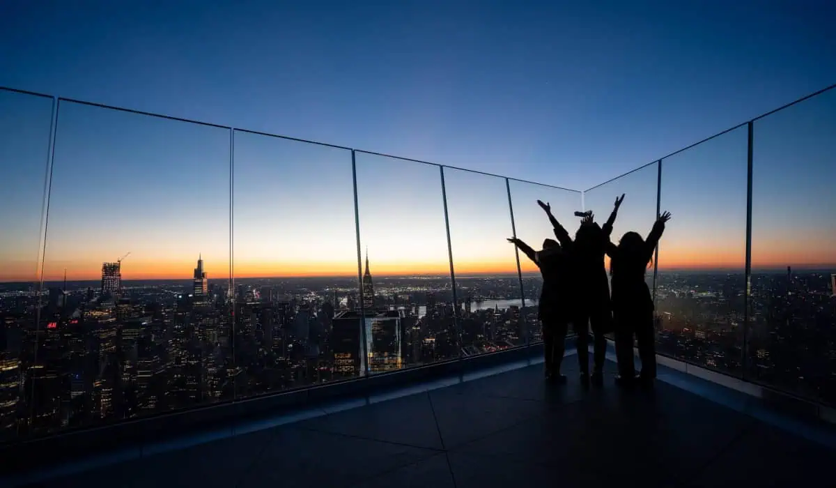 Three people raise their arms in celebration at The Edge at sunset