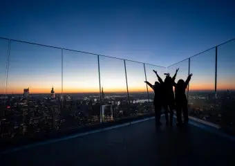 Three people raise their arms in celebration at The Edge at sunset
