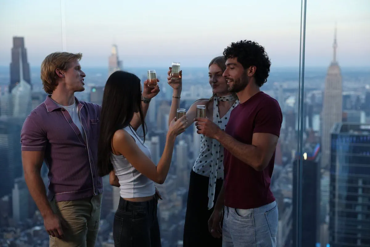 Group of friends enjoying drinks with NYC skyline view from Edge NYC sky deck.