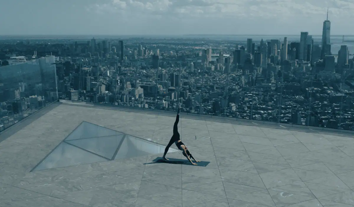 A woman does a yoga pose at The Edge overlooking New York city