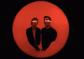 Two people with glowing eyes stand inside a red circular frame.