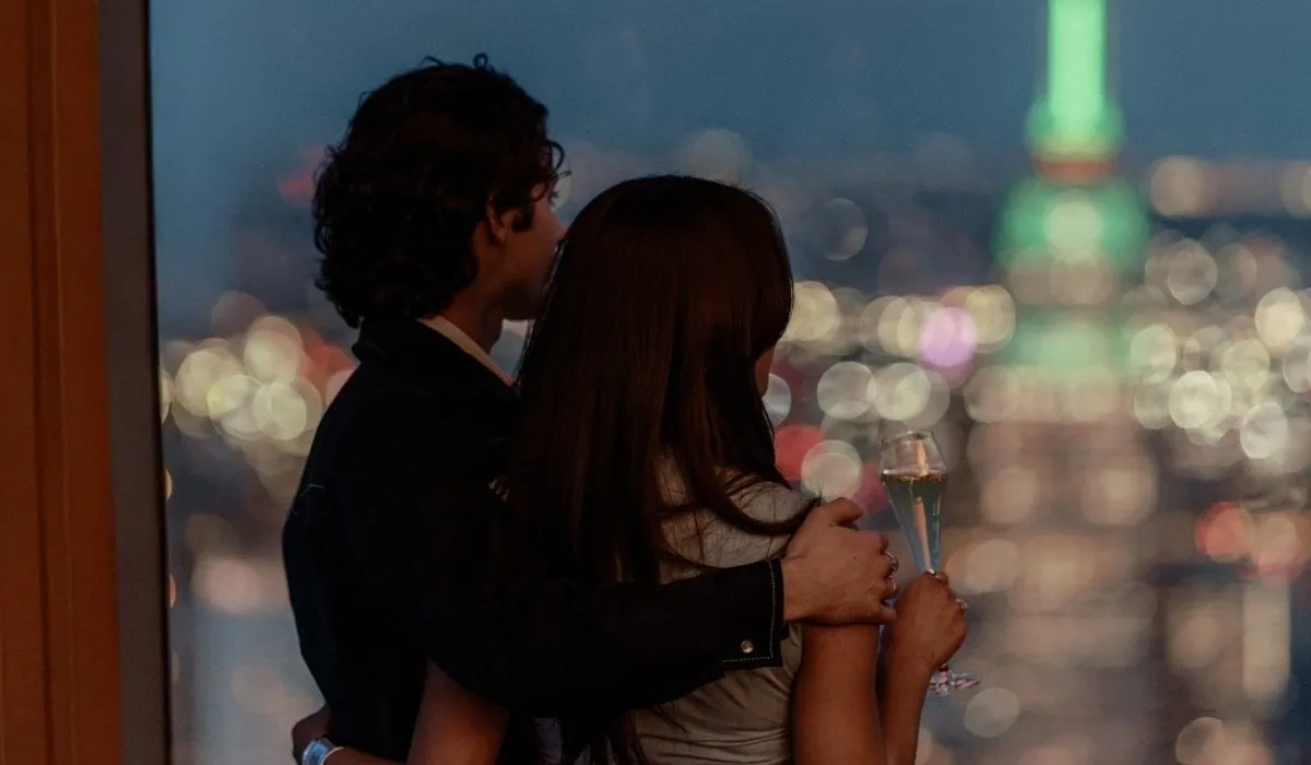 Couple on the outdoor sky deck at Edge NYC at night time, overlooking the Manhattan skyline from Hudson Yards.