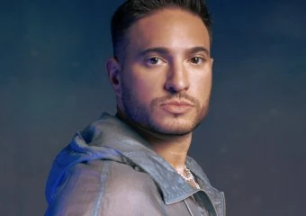Portrait of a man with dark hair and a serious expression against a dark background.