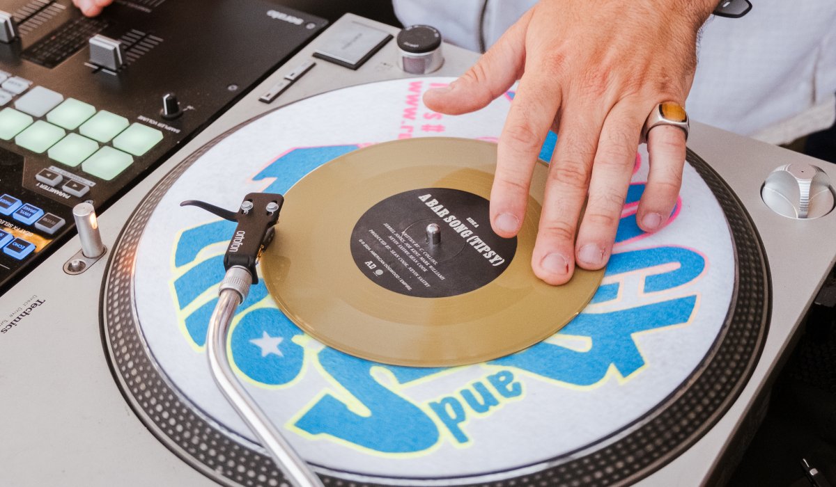 DJ mixing music with turntable and equipment at an event.