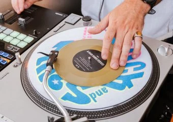 DJ mixing music with turntable and equipment at an event.