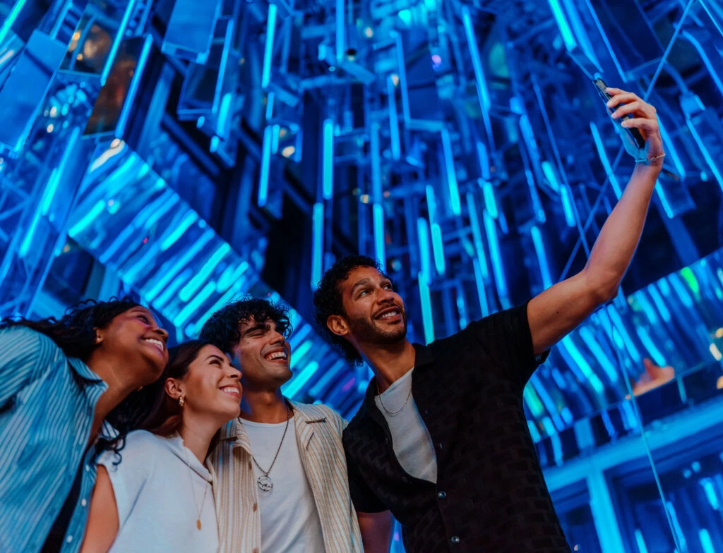 2026-Edge-MediabyAV-Reflections35 1 - Edge NYC - Edge NYC Group of friends taking a selfie at Edge NYC sky deck with vibrant blue lights.