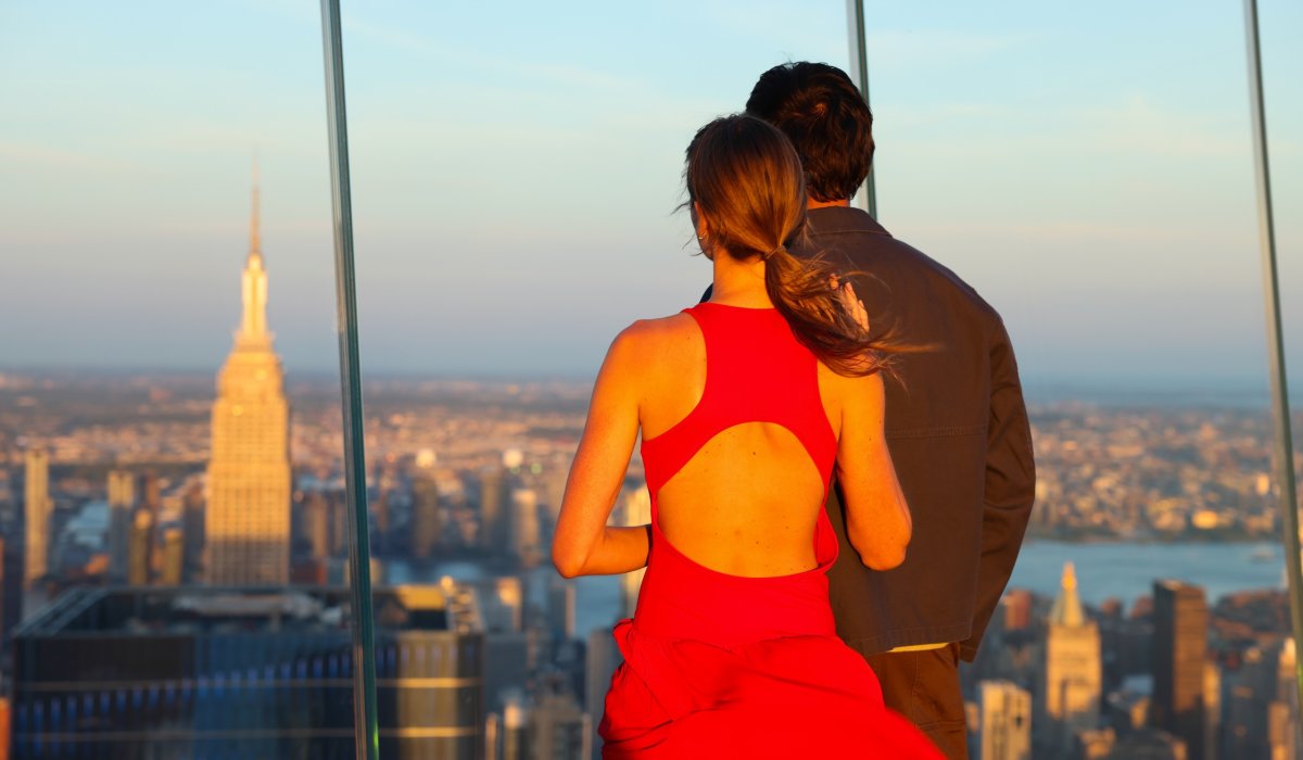 Couple on the outer deck of Edge NYC at sunset looking at the skyline in the distance.