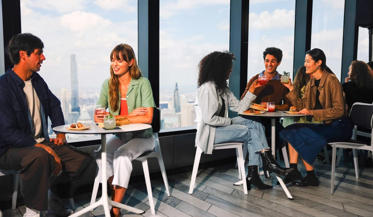 Group of diverse friends enjoying drinks and snacks at Edge NYC sky deck.