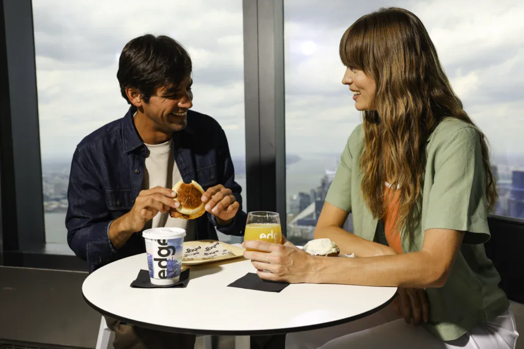 Edge NYC Skyline View with Dining Experience - Edge NYC - Edge NYC Two people enjoying food and drinks at Edge NYC with city skyline in background.