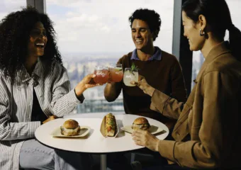 People enjoying food and drinks at Edge NYC with city skyline view.