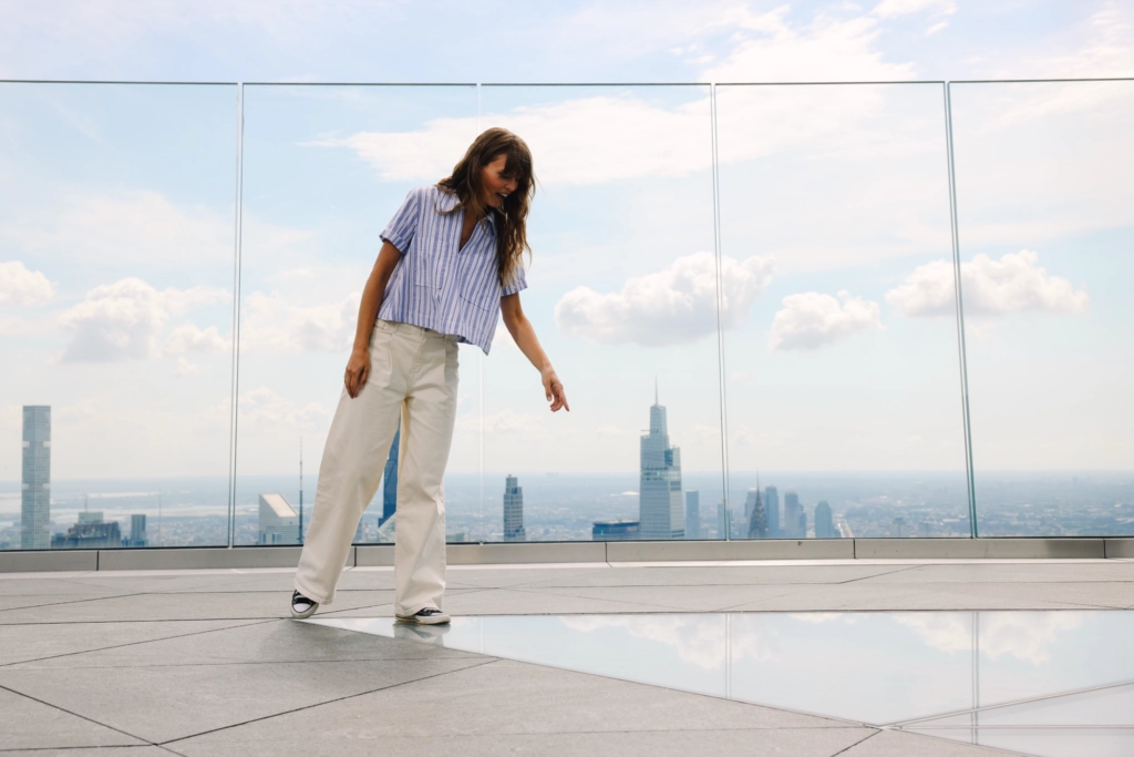 Woman enjoying view from Edge NYC sky deck - Edge NYC - Edge NYC Woman standing on Edge NYC sky deck with panoramic Manhattan skyline view.