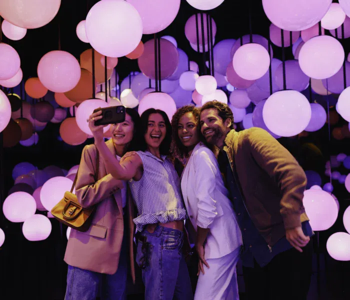 Friends taking a selfie with vibrant pink and purple lights in the background.