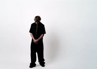Person standing with head bowed against a plain white background.